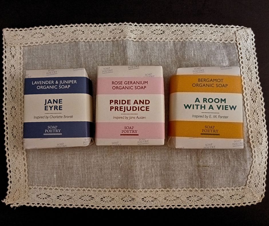 Three soap bars with literary-themed packaging on a lace doily.