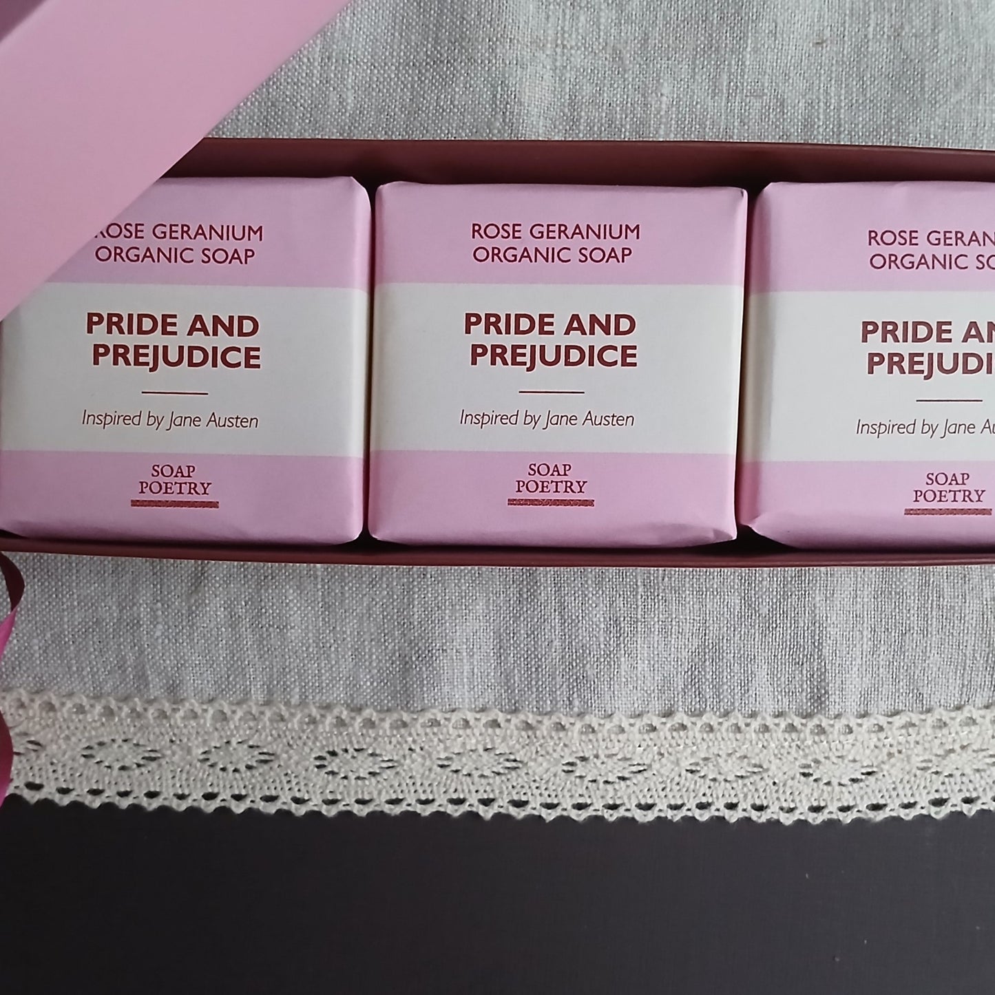 Three bars of 'Pride and Prejudice' soap inspired by Jane Austen on a pink background.