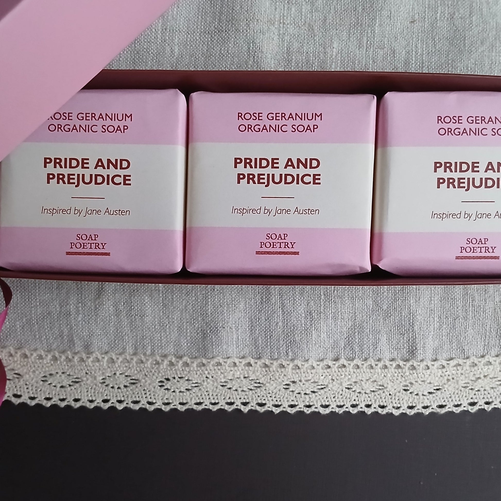 Three bars of 'Pride and Prejudice' soap inspired by Jane Austen on a pink background.