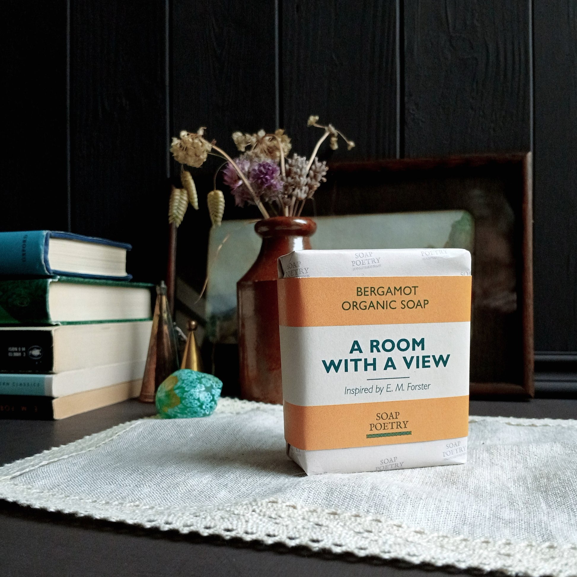 Soap package labeled 'A Room with a View' on a table with books and decor in the background