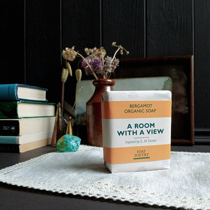 Soap package labeled 'A Room with a View' on a table with books and decor in the background