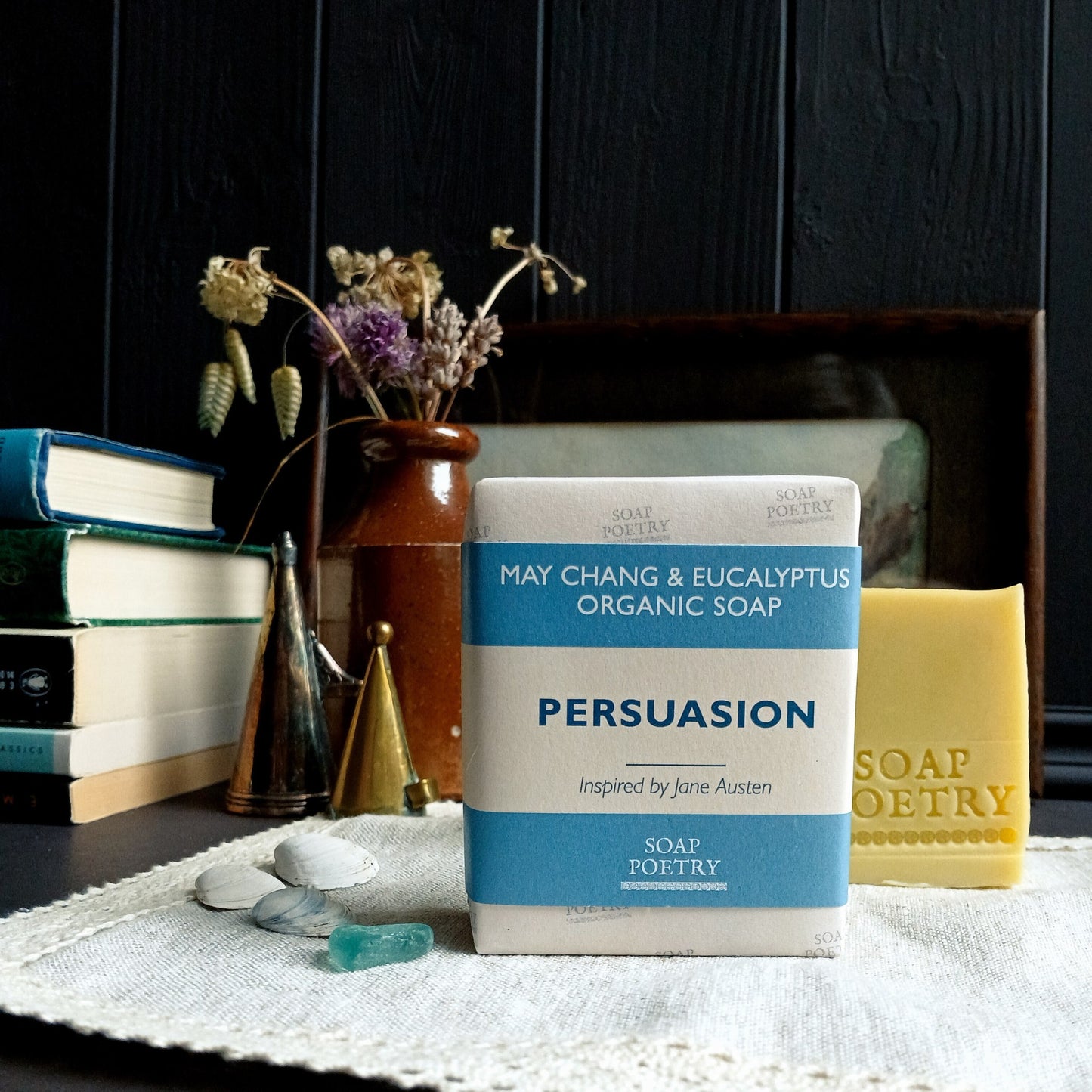 Bar of soap with 'Persuasion' packaging on a surface with books and decorative items.