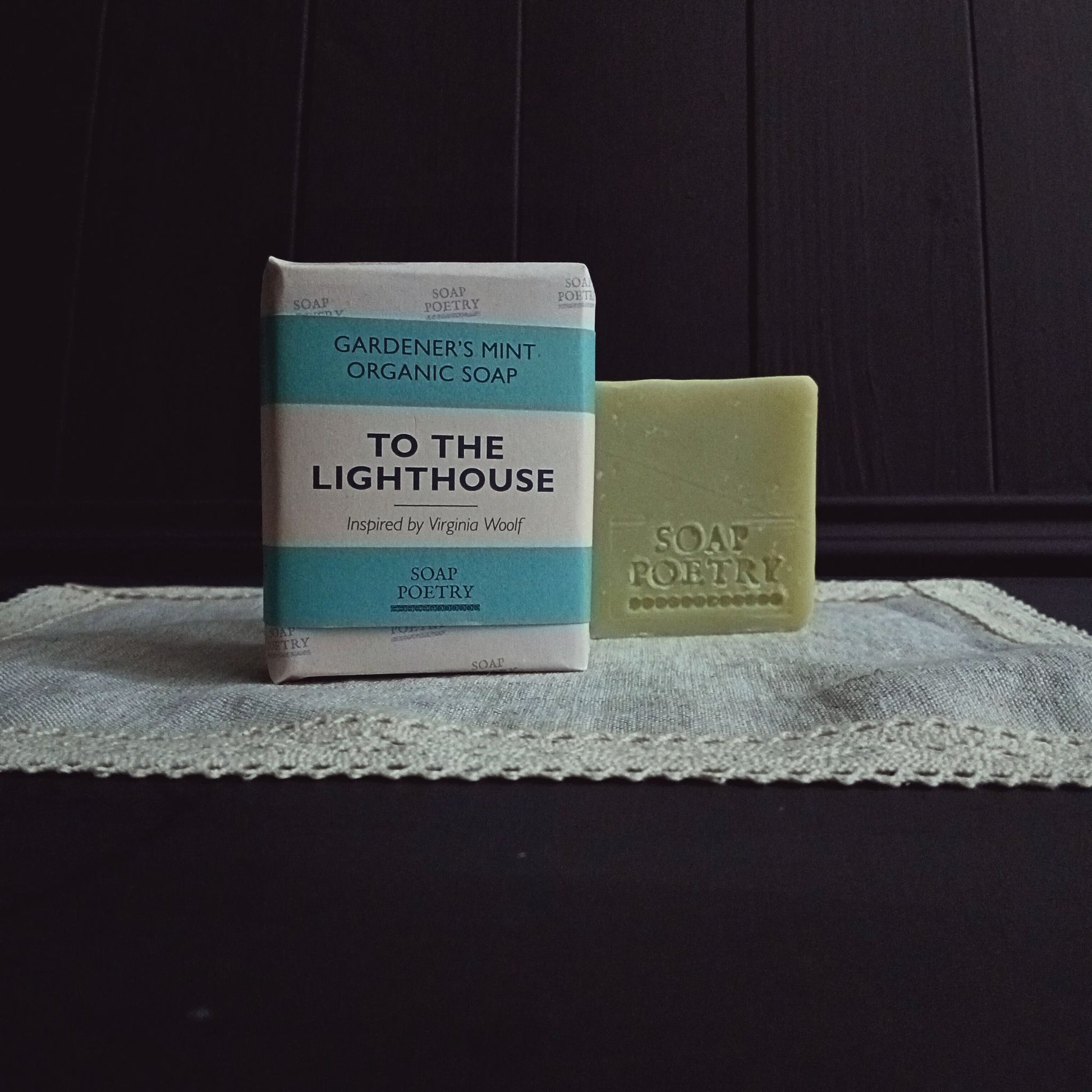 Bar of soap and packaging labeled 'To the Lighthouse' on a textured surface with dark background