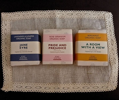 Three soap bars with literary-themed packaging on a lace doily.