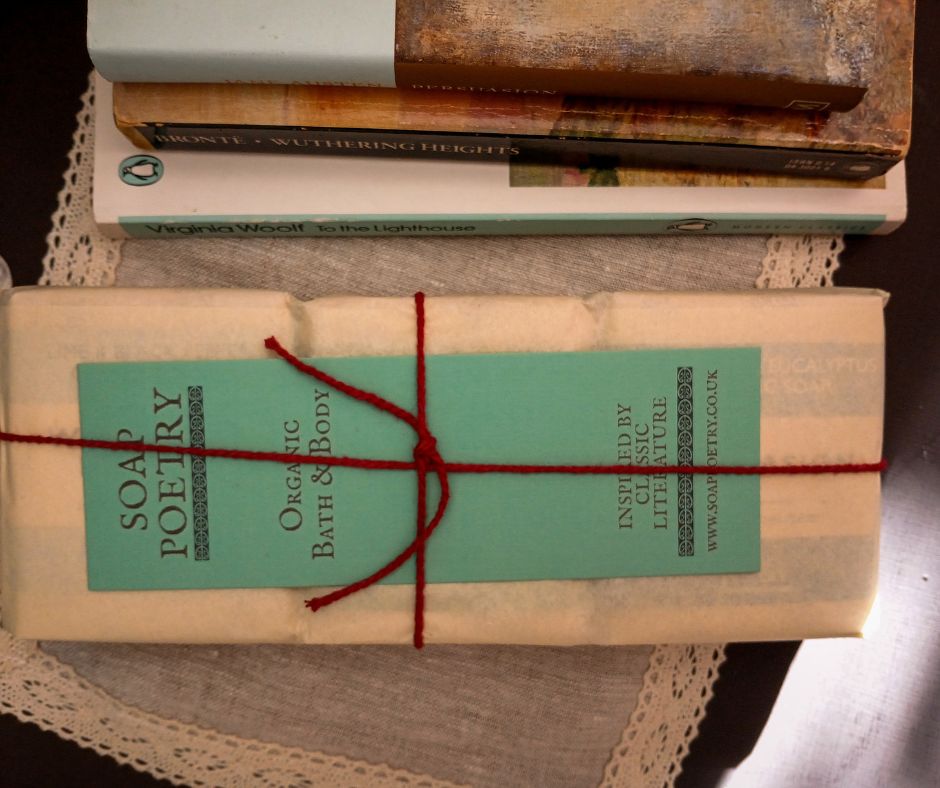 Soaps packaged with paper and tied with red cotton string, beside books, and a branded bookmark tucked beneath the string. 
