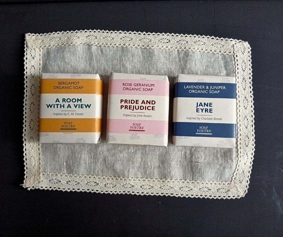 Three organic soap bars with book-themed packaging on a lace doily.