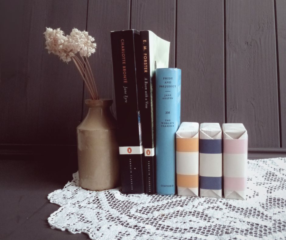 Vase with dried flowers next to books on a lace tablecloth.