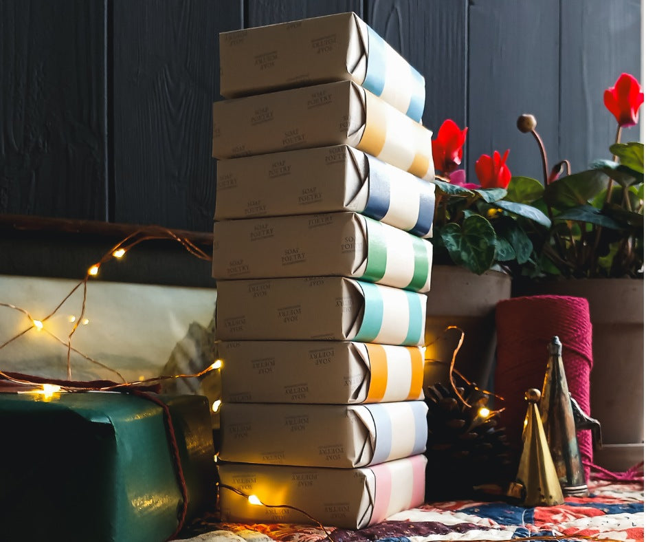 Stack of gift boxes with decorative lights and plants on a dark background