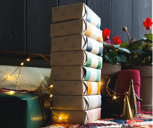 Stack of gift boxes with decorative lights and plants on a dark background