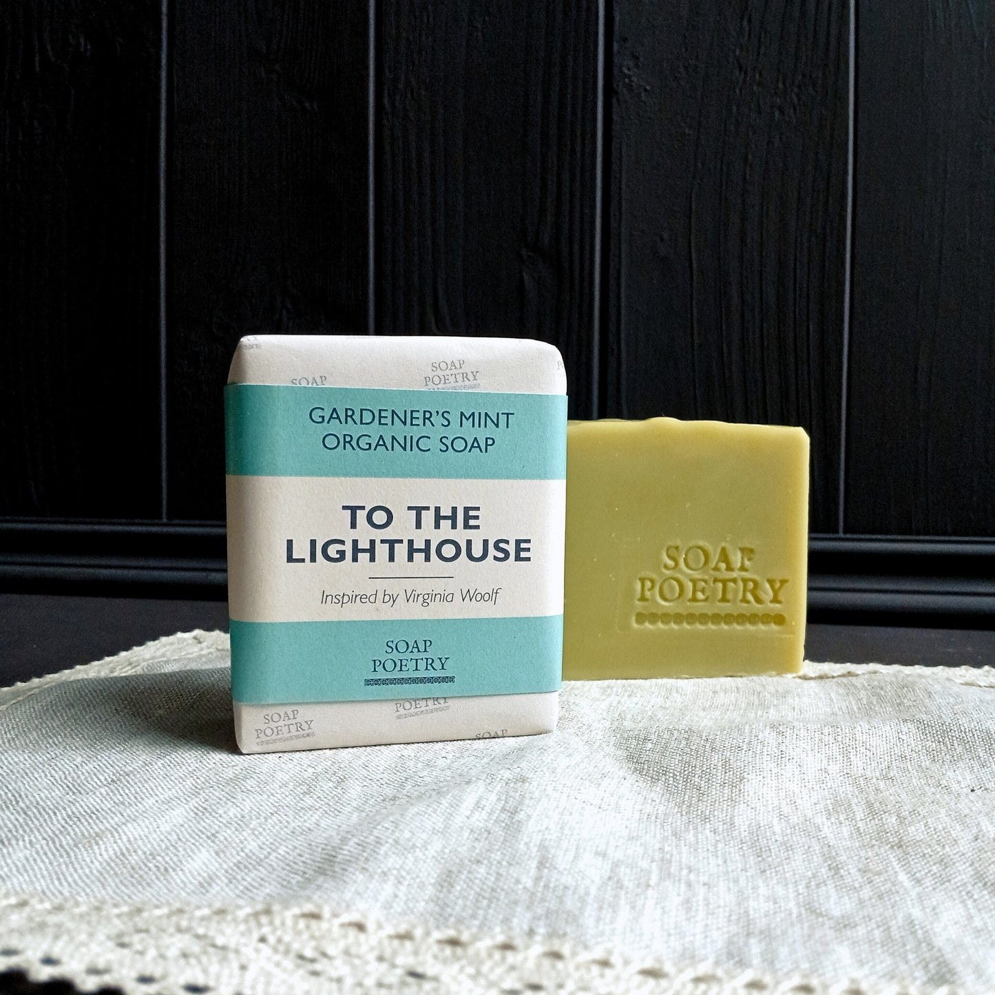 Bar of soap and packaging labeled 'To the Lighthouse' by Soap Poetry on a textured surface with dark wooden background.