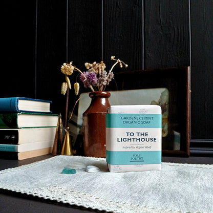 Soap bar labeled 'To the Lighthouse' on a table with books and a vase in the background.